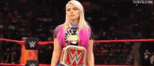 a woman is standing in a wrestling ring holding a wrestling championship .