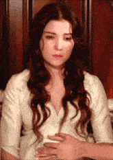 a woman in a white dress is holding her belly