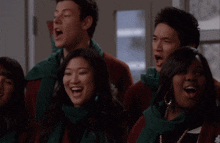 a group of people are singing in a choir wearing green scarves