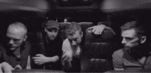 a black and white photo of four men sitting in a van