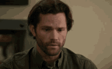 a man with long hair and a beard is looking down
