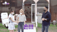 a woman wearing a mask talks to a man and another woman