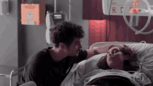 a man stands next to a woman in a hospital bed with an oxygen mask on