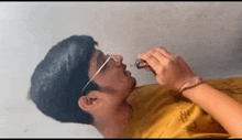 a man wearing glasses is drinking from a bottle with a syringe in his mouth .