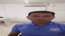 a man wearing a blue shirt with the letter b on it looks at the camera
