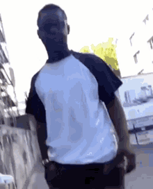a man in a white shirt and black pants is walking down a street .