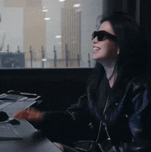 a woman wearing sunglasses is sitting at a desk with a laptop