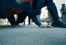 a person in a superman costume is crawling on the street