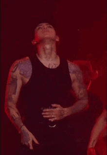 a man with a lot of tattoos on his arms is wearing a black tank top ..