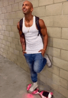 a man leaning against a brick wall with a hover board on his knee