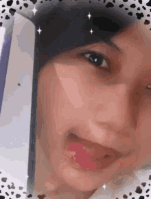 a close up of a woman 's face with her tongue out and a black hat on .