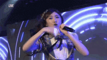 a woman is singing into a microphone while standing in front of a blue background .