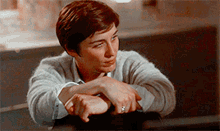 a man with a ring on his finger leans on a table