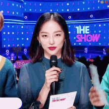a woman is holding a microphone in front of a screen that says the show