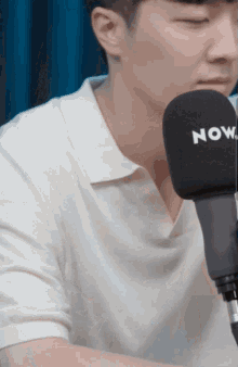 a man in a white shirt is talking into a now microphone