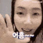 a close up of a woman 's face with a hand waving in front of her face .