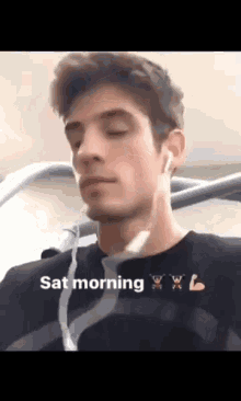 a man wearing ear buds and a black shirt with the words sat morning written on it