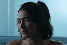 a woman without a shirt is taking a bath in a bathtub .