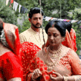 a man in a white shirt stands next to a woman in a red saree