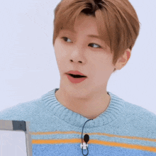 a young man wearing a blue and orange striped sweater with a microphone on his neck .