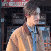 a man in a brown jacket is standing in front of a store with a sign that says aangf