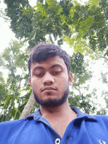 a man with a beard wearing a blue shirt with the letter l on it