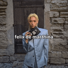 a man in a suit is holding a purse and the name felix de martina is on the bottom right