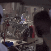 a man is looking at a robot in a room with a red box on the floor