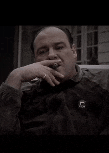 a man is smoking a cigar and wearing a fila jacket