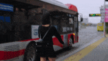 a woman is walking towards a bus with the number 3102 on the side