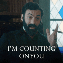 a man with a beard is holding a cigar and saying i 'm counting on you