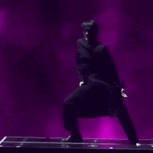 a man is dancing on a stage in front of a purple light .