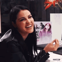 a woman is laughing in front of a poster that says 10