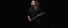 a man in a black shirt is playing a guitar in the dark .