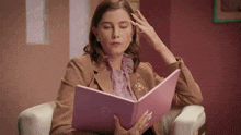 a woman is sitting in a chair reading a book