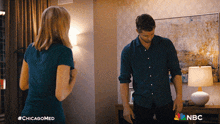 a man and a woman are standing next to each other in a room with a nbc logo on the bottom