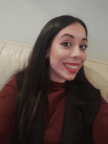 a woman with long dark hair is smiling and wearing red lipstick