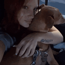 a woman with a tattoo on her wrist holds a small brown dog