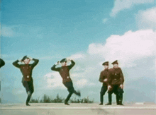 a group of men in military uniforms are dancing in front of a blue sky .