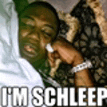 a man is sleeping on a couch with the words `` i 'm schleep '' written above him .