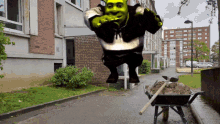 shrek is jumping in the air next to a wheelbarrow