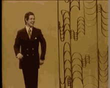 a man in a suit and tie is waving