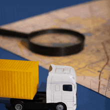 a toy truck sits next to a magnifying glass on a map