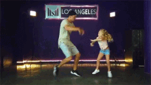 a man and a little girl are dancing together on a stage in a dance studio .