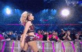 a female wrestler stands in front of a crowd and a sign that says wwe