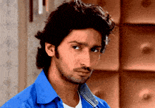 a man wearing a blue shirt and a white shirt looks at the camera