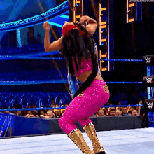 a woman in a pink outfit and gold boots is dancing on a wrestling ring .