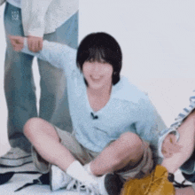 a young man is sitting on the floor with his arms outstretched and smiling