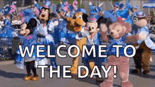 a group of mickey mouse and friends are dancing in a parade and the words welcome to the day are on the bottom .