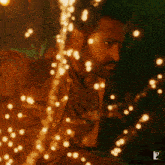 a man is surrounded by christmas lights and has a shirt that says ' ndb ' on it